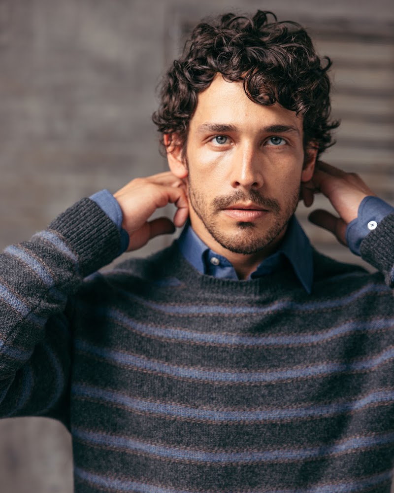 A striped lambswool crewneck worn over a blue shirt